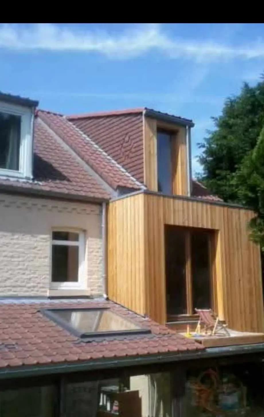 Extension en bois avec toiture en tuiles et fenêtre de toit