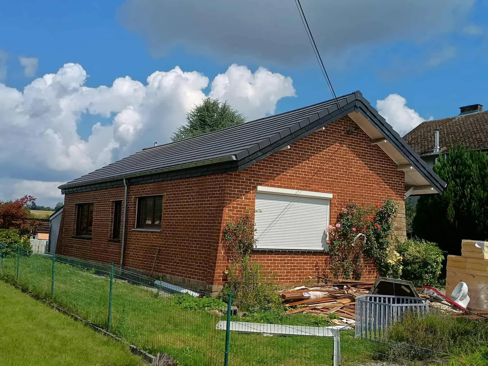 Maison en briques de plain-pied avec une toiture en tuiles noires neuves