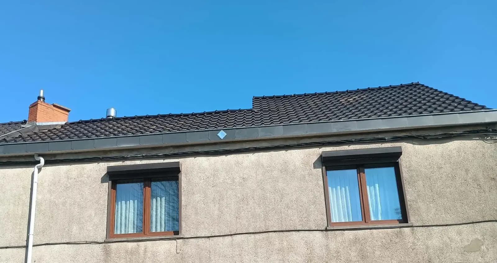 La même toiture après la pose de tuiles neuves et d'une nouvelle gouttière