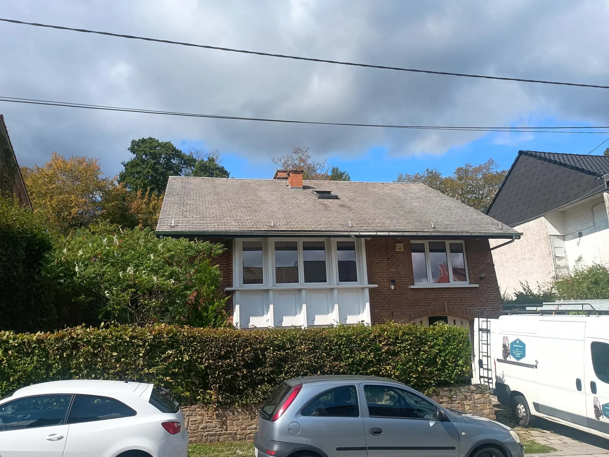 Maison en briques avec toiture en ardoises, camionnette garée devant