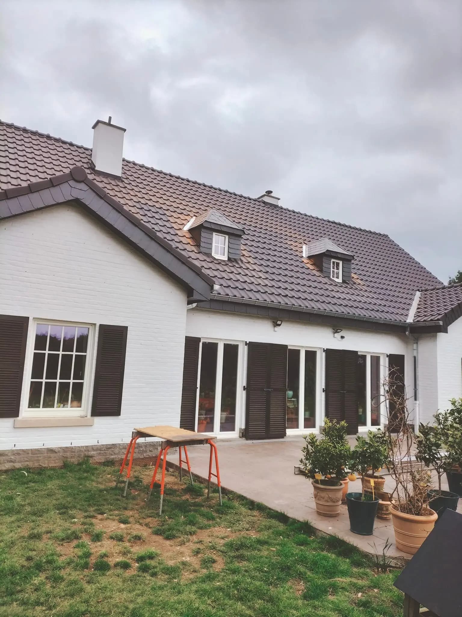 Maison blanche avec deux lucarnes et une toiture en tuiles brunes